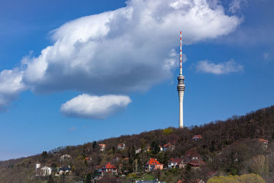 Communications tower in city against sky