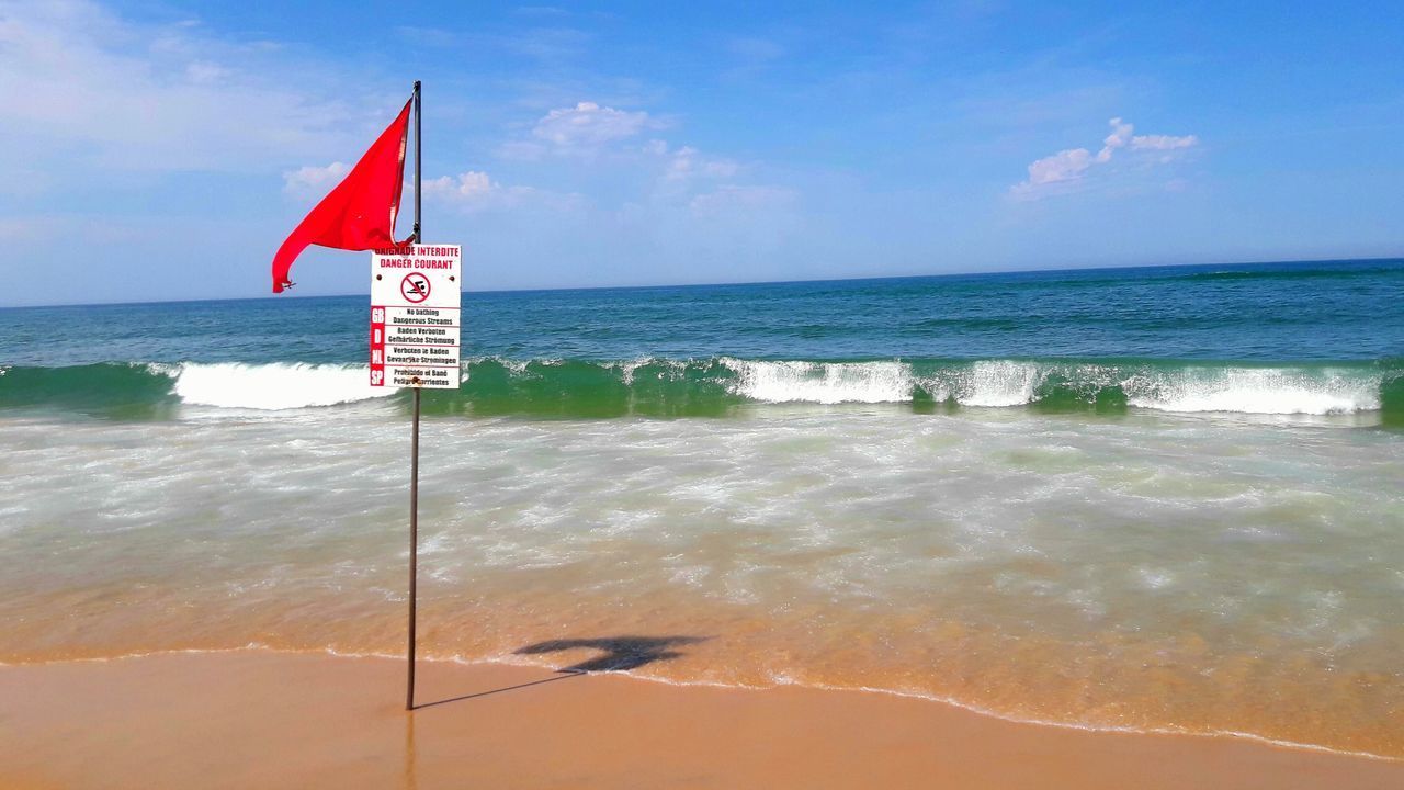 FLAG ON BEACH AGAINST SKY