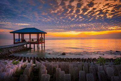 Lifeguard hut on beach against sky during sunset