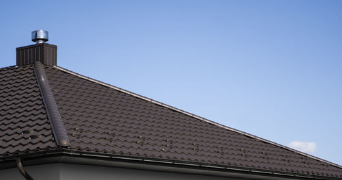 Low angle view of building roof against clear sky