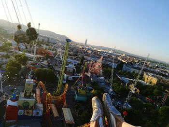 Low section of people in amusement park against cityscape