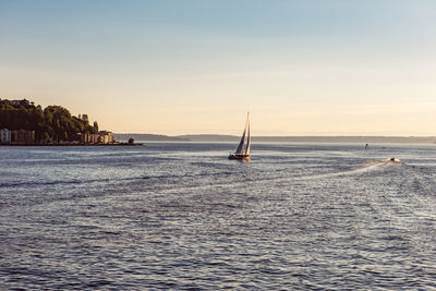 Sailboat sailing on sea against sky during sunset