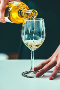 Midsection of man pouring wine in wineglass on table