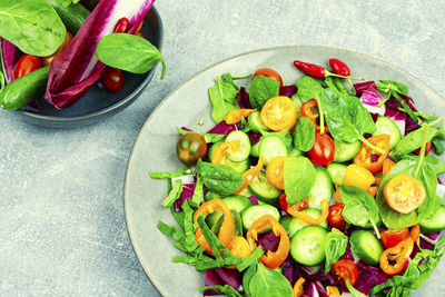 Summer vitamin salad of tomatoes, cucumbers, peppers and spinach on plate