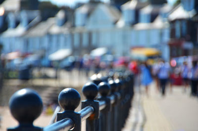 Railing by footpath in city during sunny day