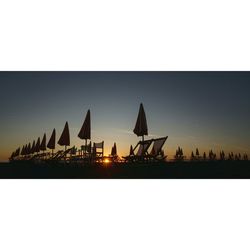 Silhouette cranes against clear sky during sunset