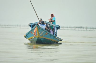 Men fishing boat in sea against clear sky