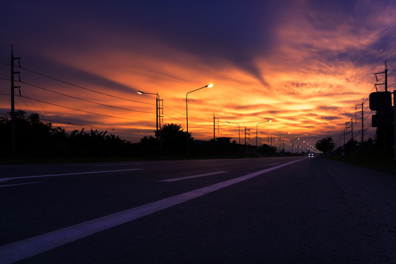 ROAD BY SILHOUETTE CITY DURING SUNSET