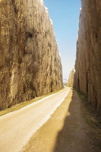 Empty road amidst rocks against clear sky