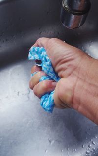 Cropped hand of woman squeezing napkin in sink