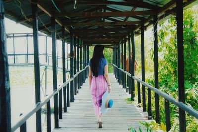 Rear view of woman walking on footbridge 