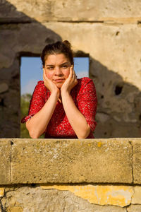 Portrait of young woman against wall