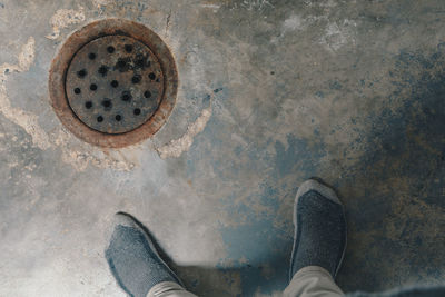 Low section of man standing by sewer in basement