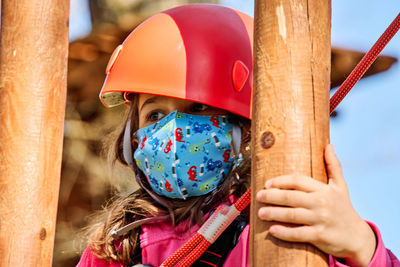 Little girl with protections practicing climbing between trees with ropes and nets