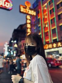 Portrait of young woman standing in city at night