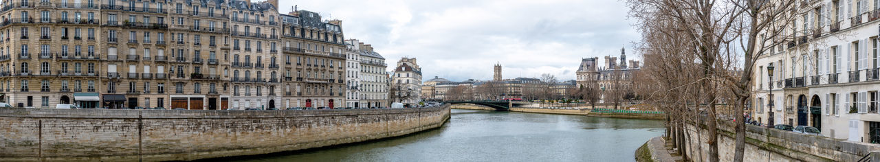 Canal amidst buildings in city against sky