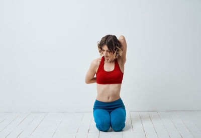 Full length of woman sitting against wall