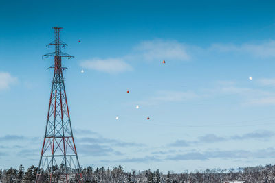 Electricity pylon against trees on field during winter