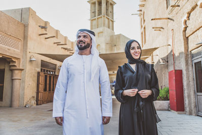 Smiling couple talking while walking on street in town