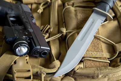 Close-up of gun and knife on bag