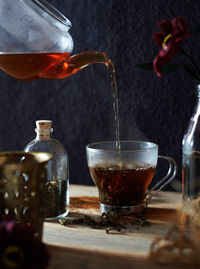 Black tea being poured in cup from teapot