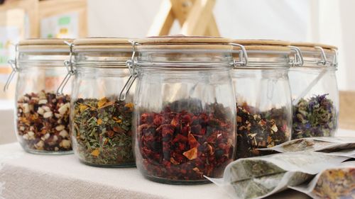 Close-up of herbs in glass jars on table