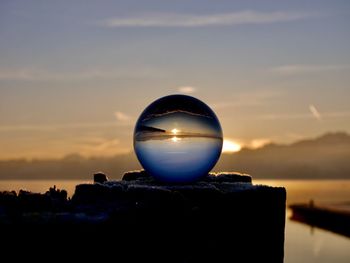 Close-up of crystal ball against sky during sunset