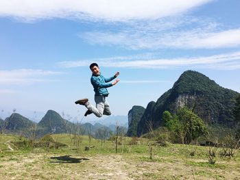 Young woman jumping on mountain against sky