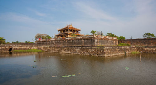 View of building by lake against sky