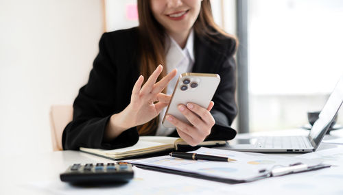 Midsection of businesswoman using laptop on table