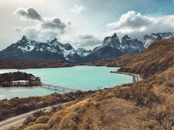 Scenic view of lake by snowcapped mountains against sky