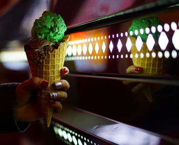 Close-up of hand holding ice cream cone at night