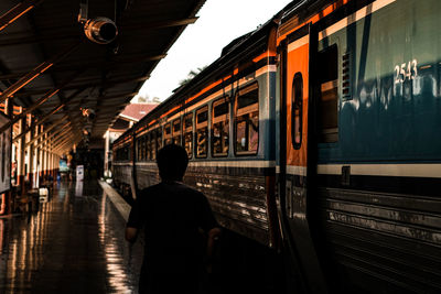 Rear view of man walking on railroad station platform