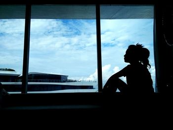 Side view of silhouette boy looking through window