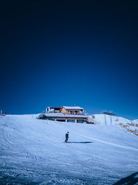 Person on snowcapped mountain against blue sky