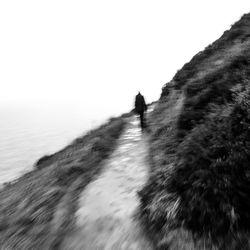 Person walking on sea shore against clear sky