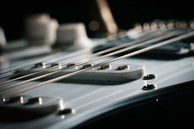 Close up picture of a black electric guitar on a black background.