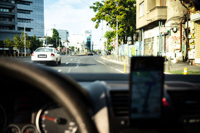 Vehicles on road in city seen through car windshield