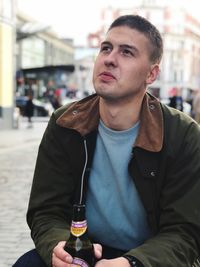 Portrait of young man drinking glass in city