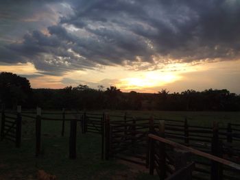 Scenic view of landscape against cloudy sky at sunset