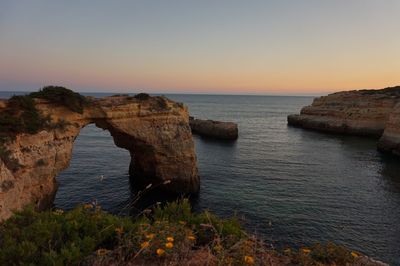 Rock formation in sea against sky during sunset
