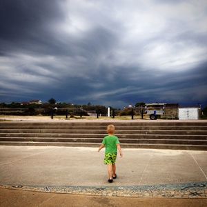 Rear view of woman standing against cloudy sky