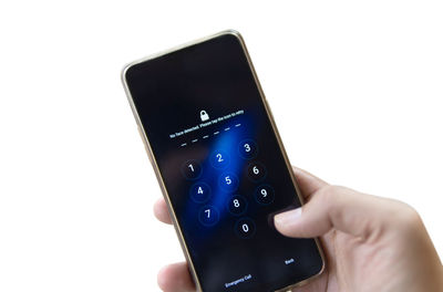 Close-up of hand holding mobile phone over white background