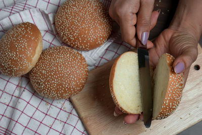 Cropped hands of woman cutting sesame seed buns