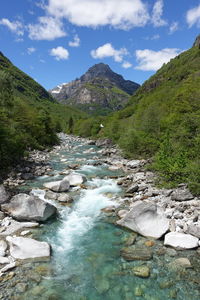 Scenic view of river stream amidst mountains against sky