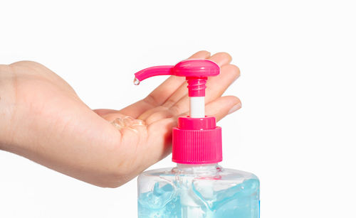 Close-up of hand holding bottle against white background