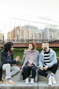 Three friends sitting in the city talking