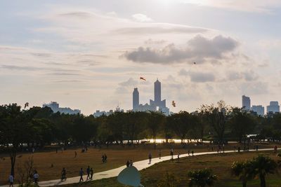 Group of people in park against cloudy sky