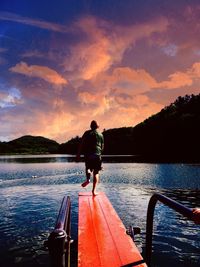 Boy on a diving board at the lake against a beautiful evening sky 