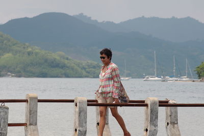 Mature woman walking on pier over sea 